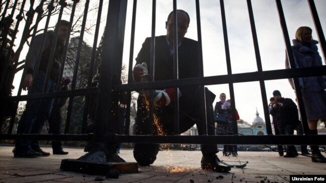 Poseł Rady Najwyższej Andrij Parubij przegląda płot w pobliżu parlamentu. Kijów, 18 listopada 2011