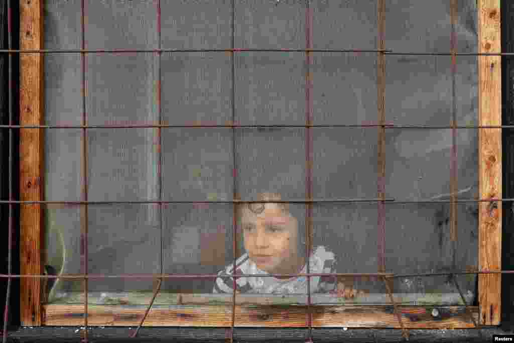 A child looks through a window inside a camp for refugees and migrants in the Belgrade suburb of Krnjaca. (Reuters/Marko Djurica)