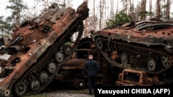 Ukrán rendőr nézi a megsemmisített orosz páncélos járműveket a felszabadított területek egyikén, Limanban 2022. október 5-én