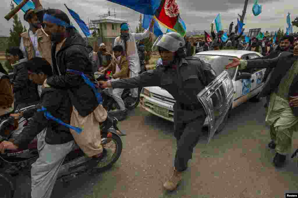 A police officer clears supporters of Afghan presidential candidate Abdullah Abdullah from the road as his convoy arrives for an election campaign rally in Herat Province on April 1. (Reuters/Zohra Bensemra)