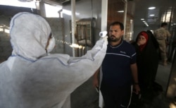 A member of a medical team checks the body temperature of an Iraqi man upon arrival at the Shalamcheh border crossing with Iran, east of Basra city, on February 20.