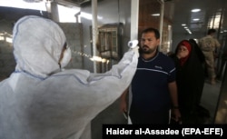 A member of a medical team checks the body temperature of an Iraqi man upon arrival at the Shalamcheh border crossing with Iran, east of Basra city, on February 20.