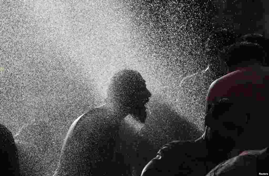 An antigovernment protester takes a morning bath with others at a public pump during the Revolution March in Islamabad, Pakistan. (REUTERS/Akhtar Soomro)