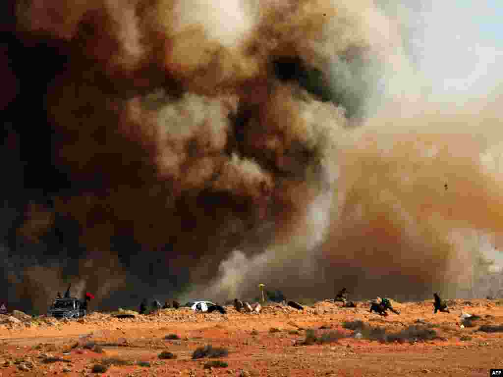 Libyan rebel fighters run for cover as bombs are dropped near the key oil port of Ras Lanuf. Photo by Roberto Schmidt for AFP