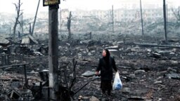 A woman picks her way through the rubble in Grozny during the Second Chechen War in February 2000. 