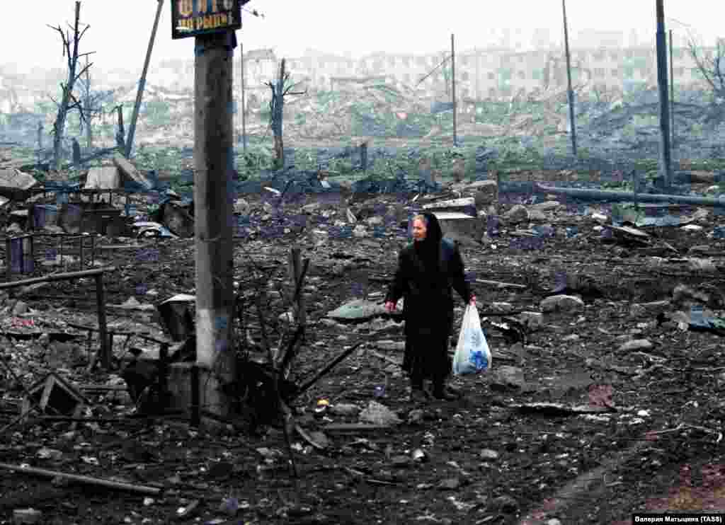 A woman picks her way through the rubble in Grozny. After being targeted twice in less than a decade, Chechnya&rsquo;s capital was the most destroyed city on earth.