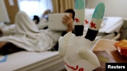 A medical glove painted as a Syrian opposition flag is pictured near the bed in Tripoli, LIbya, of a Syrian activist who sustained injuries during shelling on the Homs area of northern Syria last month.