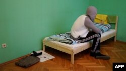 A man who fled persecution in Chechnya due to his sexual orientation sits on his bed in Moscow.