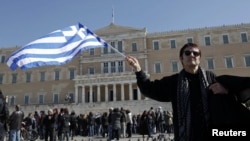 A woman waves a Greek flag during an anti-austerity rally in front of the parliament in Athens on February 19.