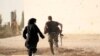 A female reporter runs with a rebel fighter to avoid snipers on the front line against Islamic State fighters in Aleppo's northern countryside in October. 