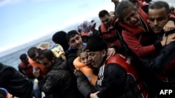 Refugees and migrants with their children, arrive at the Greek island of Lesbos, after crossing the Aegean sea from Turkey on October 2, 2015. 