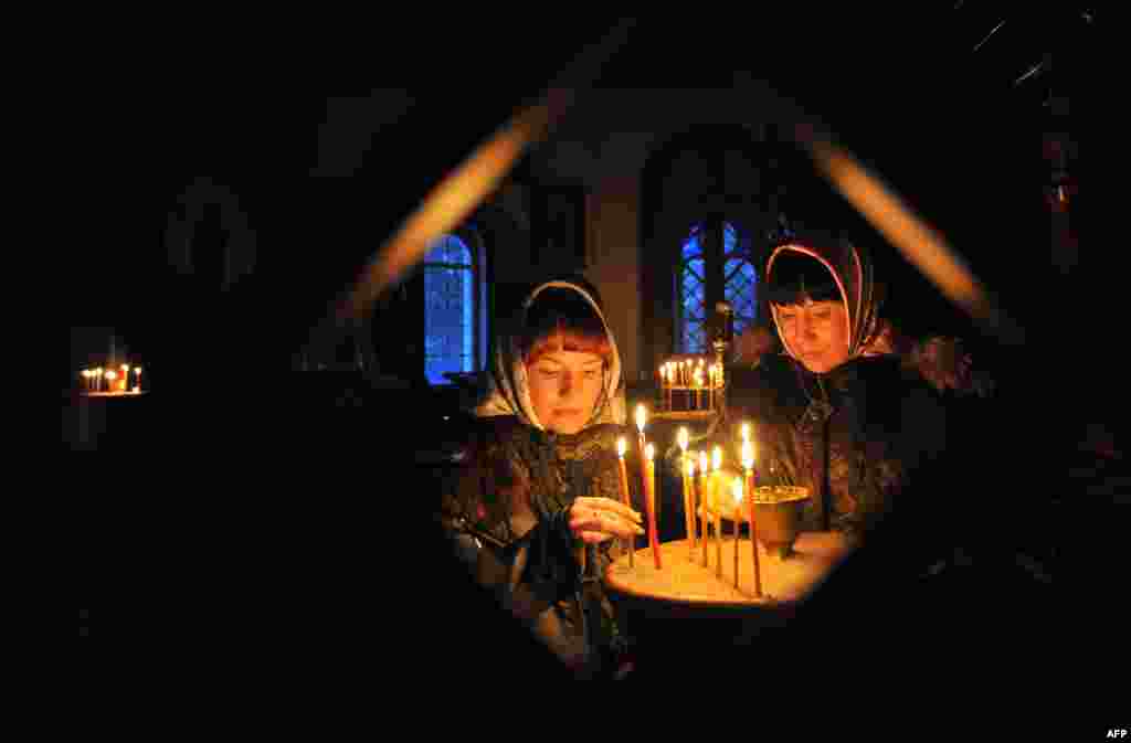 Two sisters light candles during an Orthodox Christmas service in a church in the Kyrgyz village of Sokuluk, near the capital, Bishkek. (AFP/Vyacheslav Oseledko)