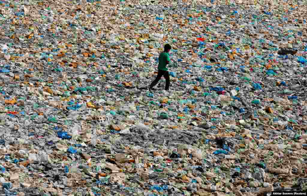 A boy walks over a drainage channel littered with heaps of polythene bags on Earth Day in Karachi, Pakistan, on April 22. (Reuters/Akhtar Soomro)