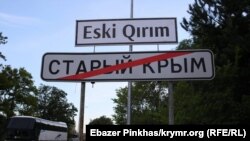 Дорожній покажчик міста Старий Крим. Вгорі історична кримськотатарська назва міста латиницею. Крим, 2019 рік