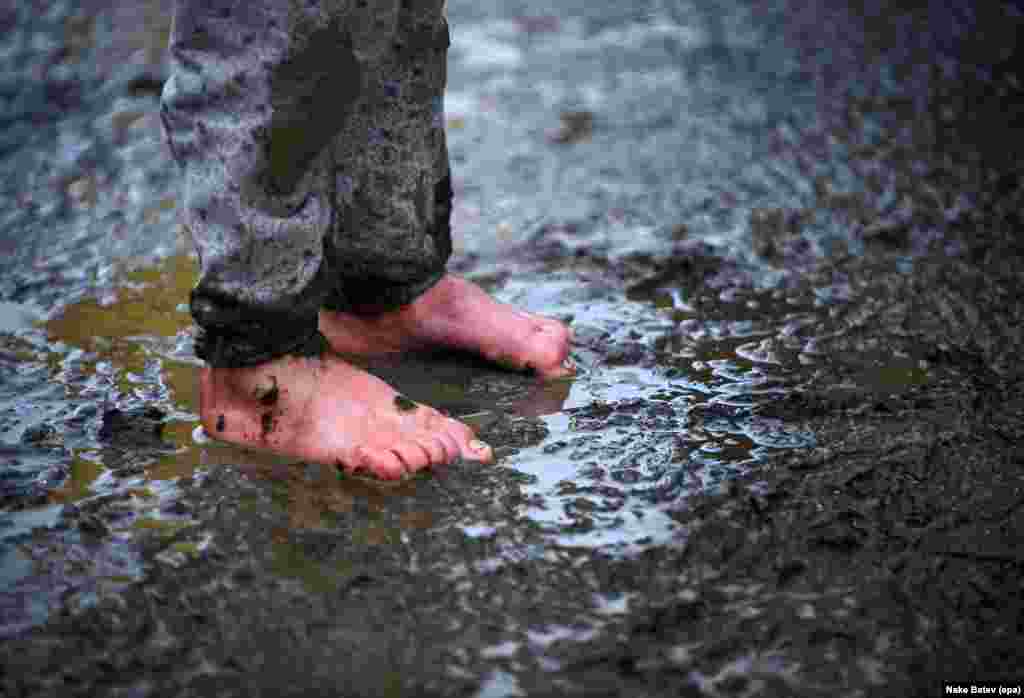 A migrant &nbsp;boy stands barefoot in the mud at a refugee camp on the border between Greece and Macedonia on March 16. (epa/Nake Batev)