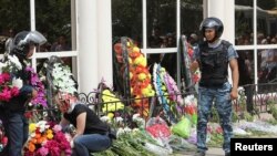 Женщина возлагает цветы у оружейного магазина в день похорон погибшего от рук предполагаемых исламистов продавца Андрея Максименко. Актобе, 8 июня 2016 года.