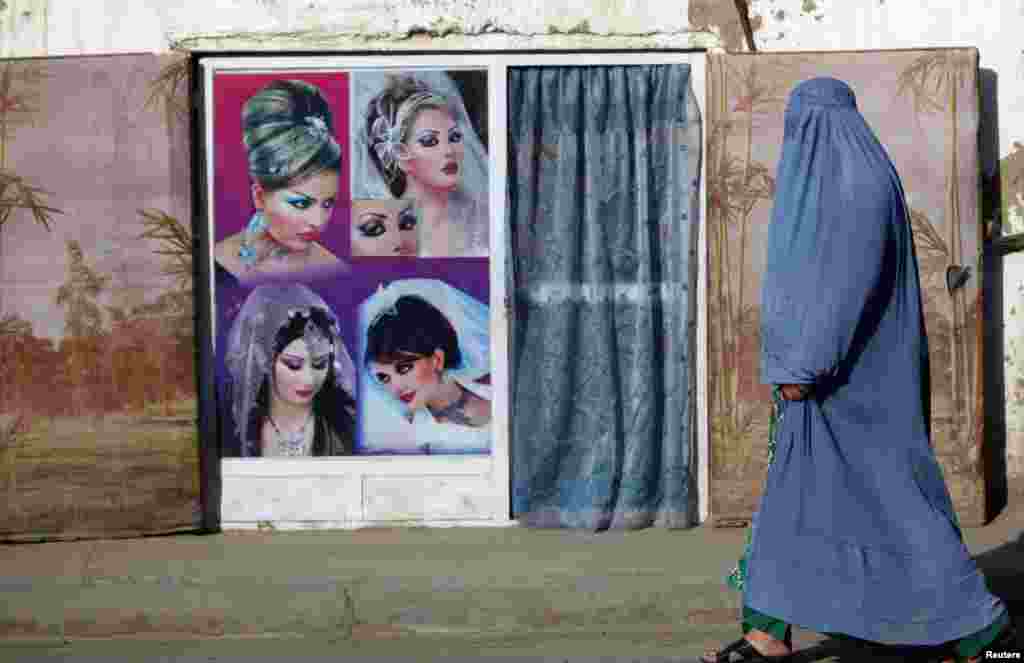 A woman in a burqa walks past a beauty salon in Kabul. (Reuters/Mohammad Ismail)