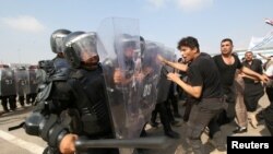 A plainclothes police officer, acting as a protester, attacks riot police during a graduation ceremony in Basra, Iraq November 12, 2018 REUTERS/Essam al-Sudani