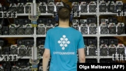 An employee inspects machines for the production of bitcoins at the CryptoUniverse mining center in Kirishi, Russia. To “mine” cryptocurrencies like bitcoin, you need powerful computers and cheap electricity. (file photo)