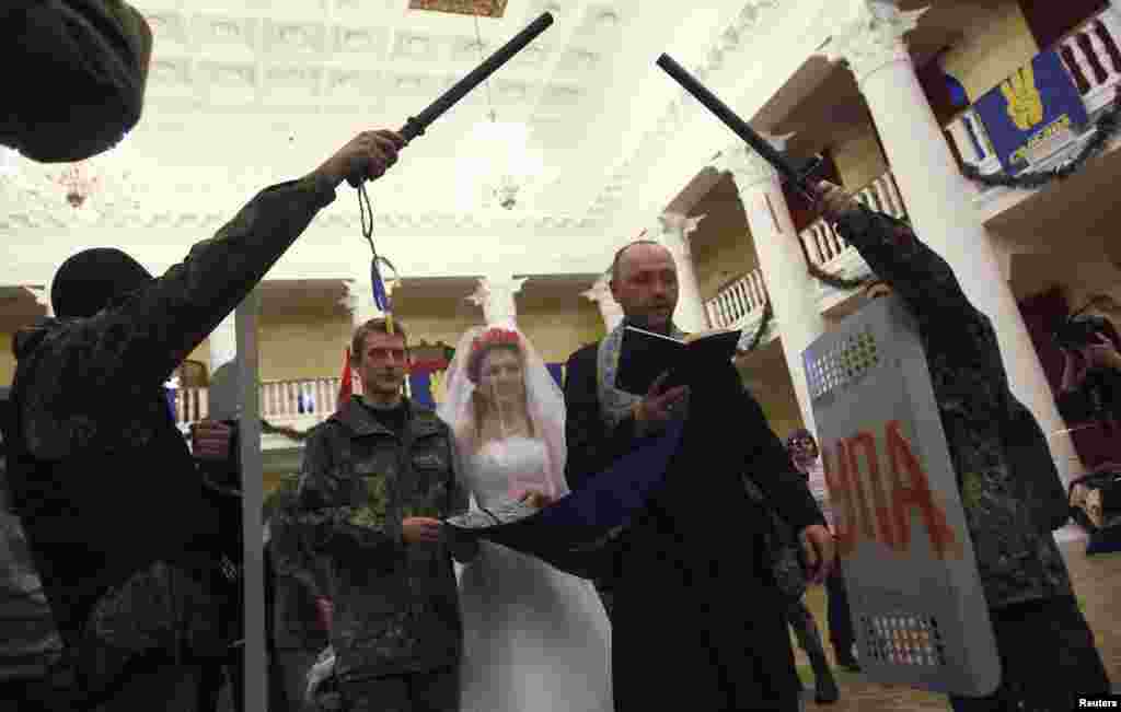 Ukrainian antigovernment protesters Bogdan (second left), 21, and Yulia, 25, hold their wedding ceremony in a city municipality building occupied by protesters in Kyiv on February 5. (Reuters/David Mdzinarishvili)