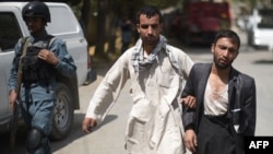 A wounded Afghan man (R) is assisted at the site of a suicide car bomb in Paghman district, near Kabul on September 16.