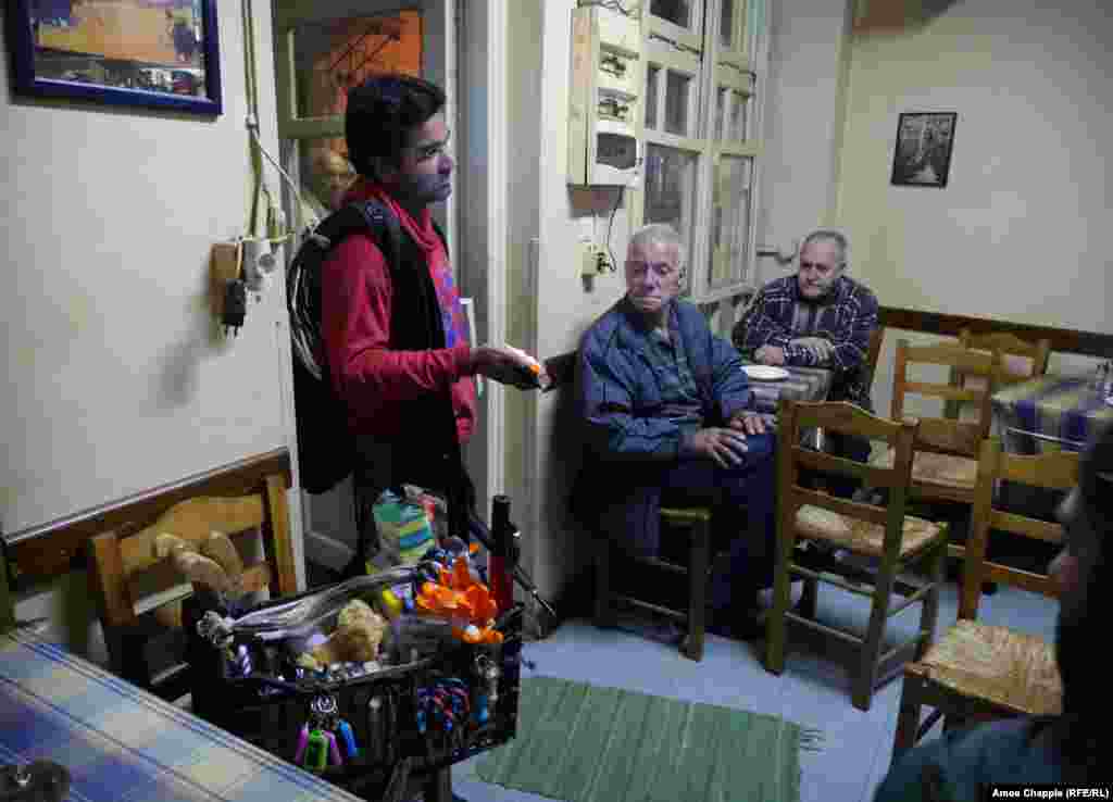 Pakistani hawker&nbsp;Amjad&nbsp;Ali tries to interest the&nbsp;taverna&nbsp;crowd in a&nbsp;flashlight that he eventually sold, along with three knives from his basket of&nbsp;goods.