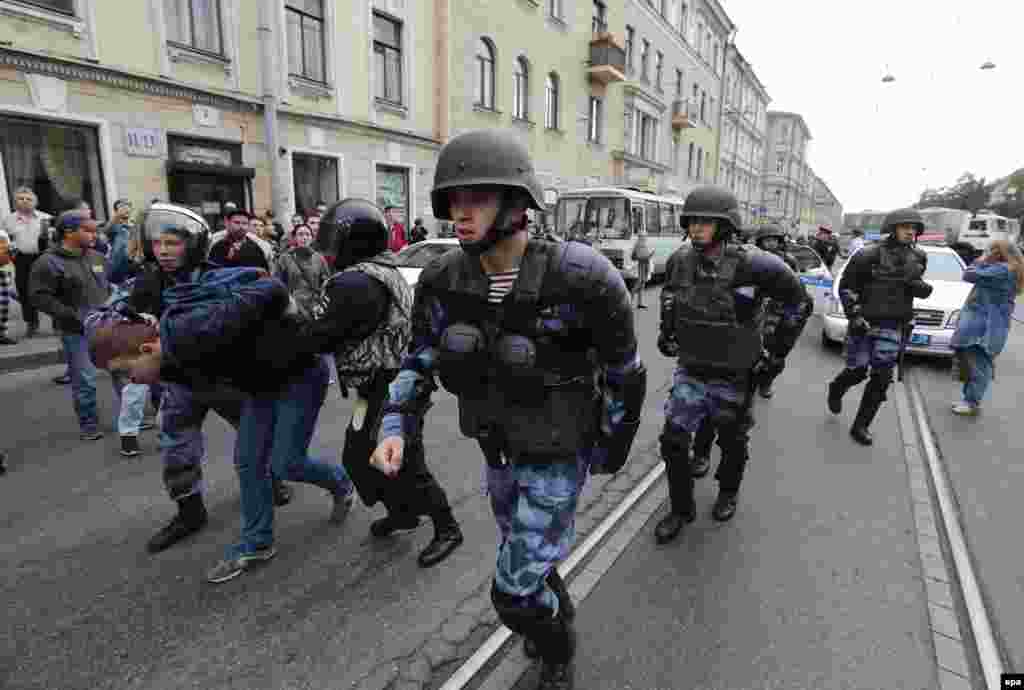 Police wearing ballistic helmets advance up a street in St. Petersburg.&nbsp;