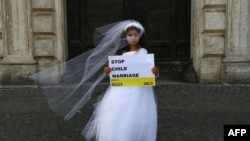 تصویر آرشیف: یک دختر خُرد سال با پوشیدن لباس نو عروس٬ این شعار را به دست گرفته است: « ازدواج اطفال را متوقف کنید!» 