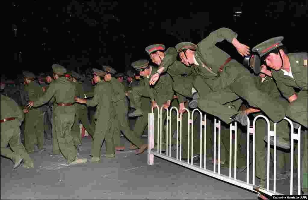People Liberation Army (PLA) soldiers leap over a barrier on Tiananmen Square in central Beijing during heavy clashes with people and dissident students on June 4, 1989.