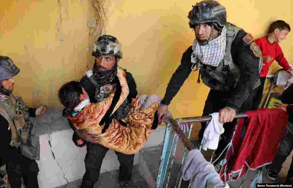 Iraqi special forces soldiers assist a woman injured during fighting on February 28.&nbsp;