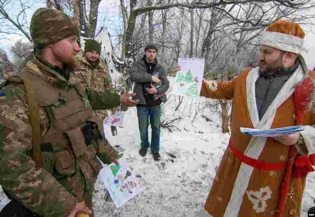 Волонтер, одягнений в костюм Святого Миколая, дарує військовим малюнки дітей. Передові позиції українских військових біля Волновахи, Донецька область, 28 грудня 2016 року