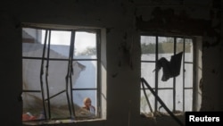 A girl peers through the damaged windows of a classroom, one of scores attacked in Pakistan and Afghanistan by militants who object to what they regard as un-Islamic teachings.