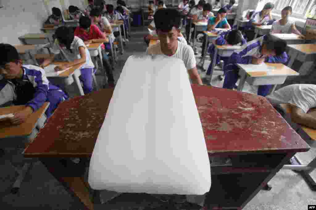 A huge ice cube is placed on a desk to lower the temperature inside a classroom in Jinan in eastern China. Temperatures reached 35.7 Celsius. (AFP)