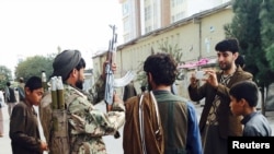 A Taliban fighter (2nd L) poses for a photo at the main square in Kunduz on September 29.