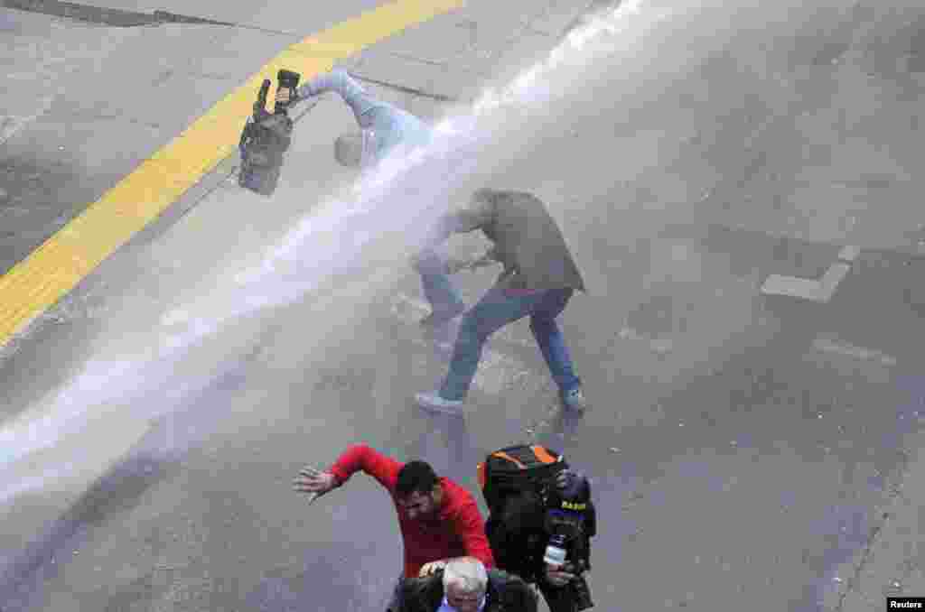 Media personnel run as riot police use water cannon to disperse protesters outside the Supreme Electoral Council in Ankara on April 1. (Reuters)