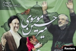 A photo from 2009 showing women walking past a picture of then presidential candidate Mir Hossein Musavi (right) and former President Mohammad Khatami in Tehran.