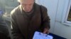 Мікола Чарнавус на рынку ў Баранавічах з подпісамі прадпрымальнікаў пад лістом да ўладаў
