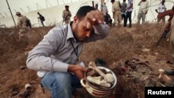 A man collects human remains at the site of a mass grave in Tripoli on September 25.