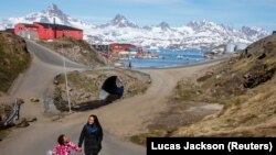 Жена с дете се разхожда в град Тасилак, Гренландия.