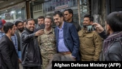 Мужчины делают селфи на свои смартфоны с командующим силами США и НАТО в Афганистане генералом Остином Скоттом Миллером и с исполняющим обязанности министра обороны Афганистана Асадуллой Халидом (в центре справа) в Кабуле. 26 февраля 2020 года. Иллюстрационное фото
