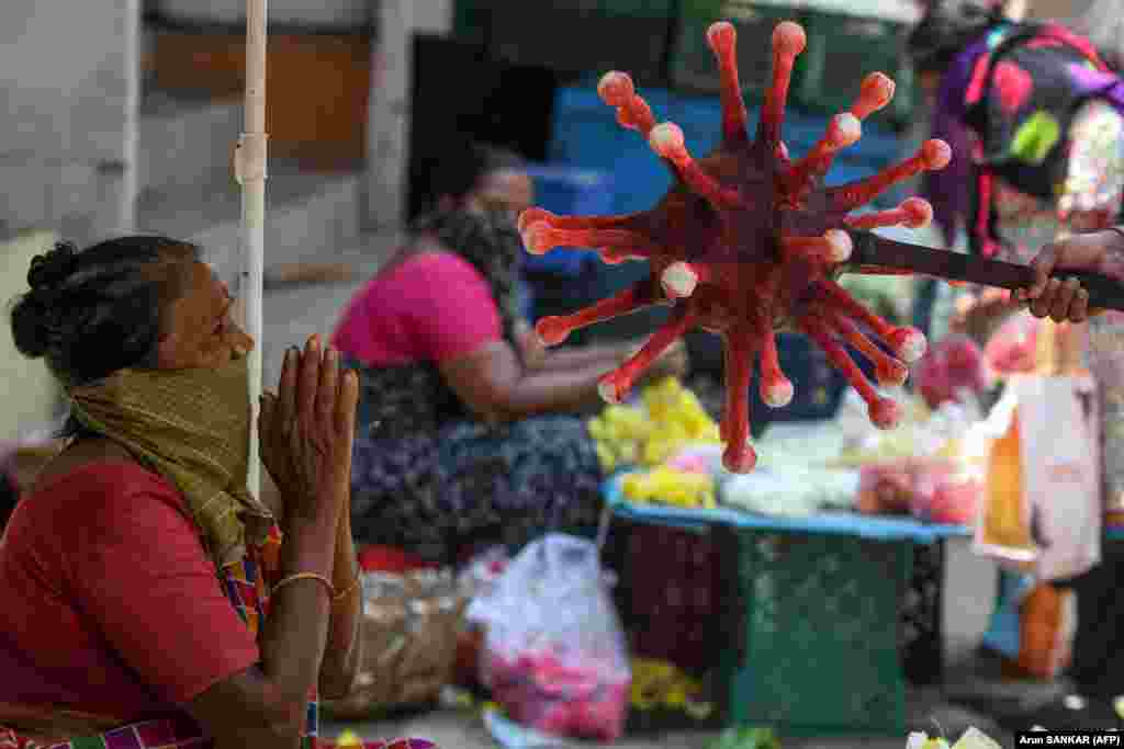 A policeman points a coronavirus-themed baton toward a market vendor in Chennai, India, to raise awareness about physical distancing.