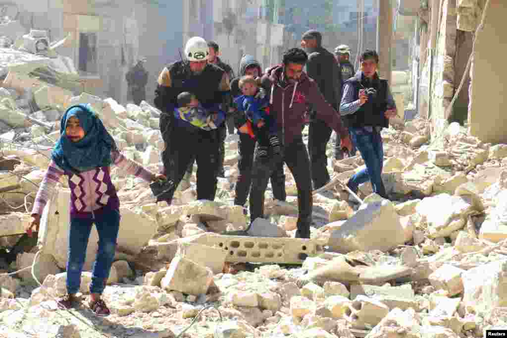 Civilians and rescue workers carry children at a damaged site following an air strike on the rebel-held city of Idlib in Syria. (Reuters/Ammar Abdullah)