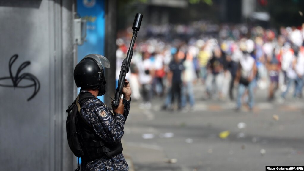 Боец Национальной боливарианской гвардии Венесуэлы напротив оппозиционных демонстрантов. Каракас, 23 января