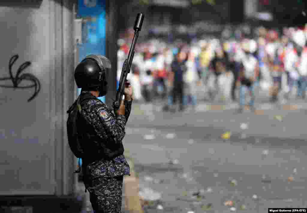 An officer takes his position as thousands demonstrate in Caracas.