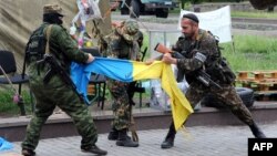 Боевики группировки «ДНР», которая в Украине официально признана террористической, разрывают флаг Украины. Донецк, 29 мая 2014 года