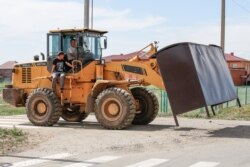Трактор устанавливает автобусную остановку в селе Кызылсуат. Акмолинская область, 10 июня 2020 года.