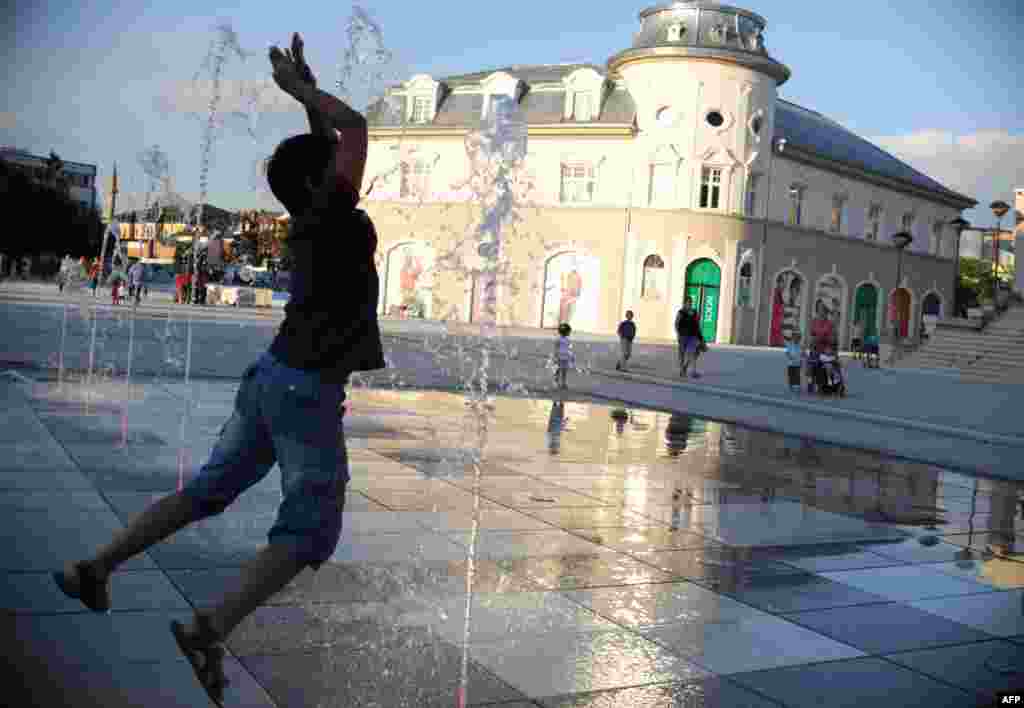 A boy cools off in a fountain during sunset in Pristina, Kosovo. (AFP/Armend Nimani)