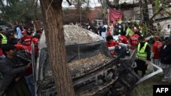 Volunteers and journalists representatives examine the wreckage of a vehicle after a suicide bomb attack in Peshawar on February 15.