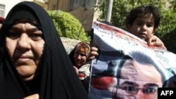 A young relative of Iraqi journalist Muntadhir al-Zaidi holds up his picture during his trial in March.