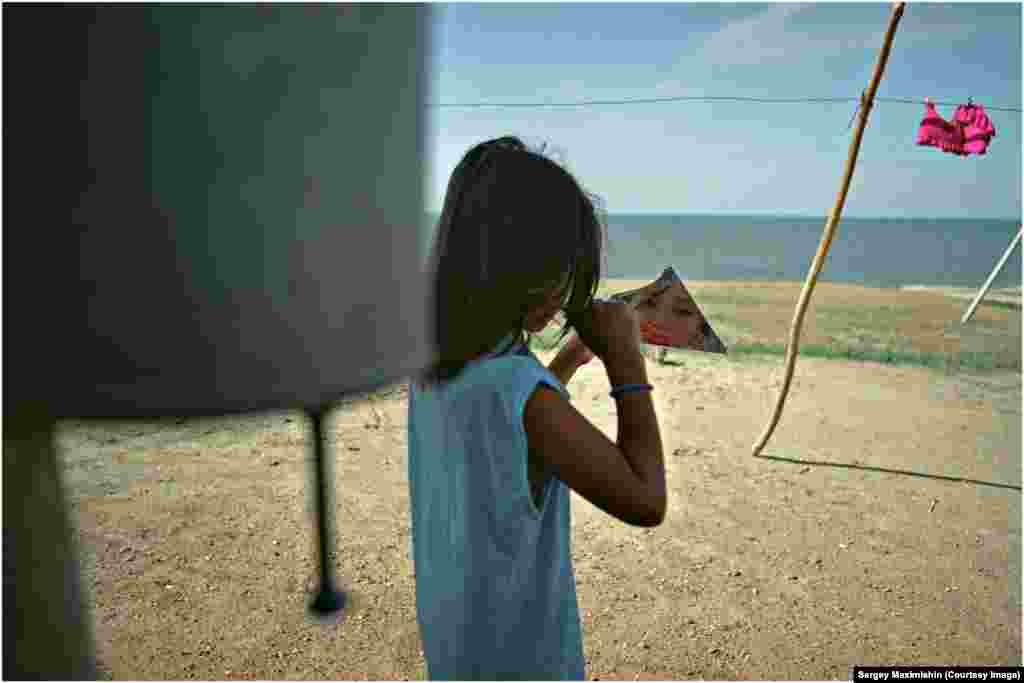 A girl with a broken mirror on the shore of Zaisan Lake, Kazakhstan, 2005